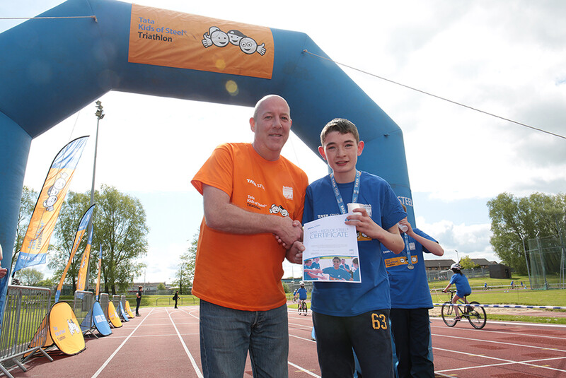 A winner at the Tata Steel kids triathlon being congratulated with a certificate of achievement A winner at the Tata Steel kids triathlon being congratulated with a certificate of achievement