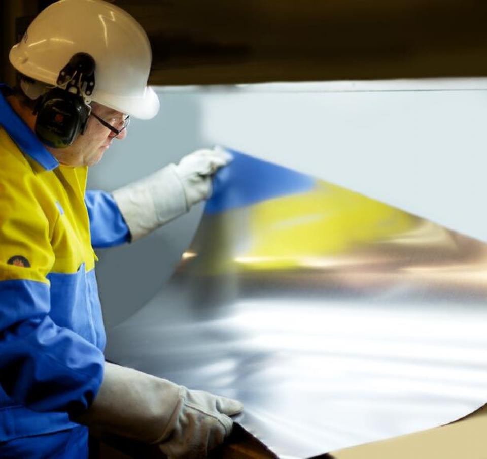 Packaging steel sheet being examined by Tata Steel employee wearing protective equipment Packaging steel sheet being examined by Tata Steel employee wearing protective equipment