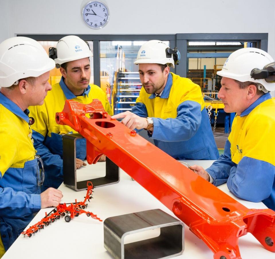Tata Steel workers looking at steel part