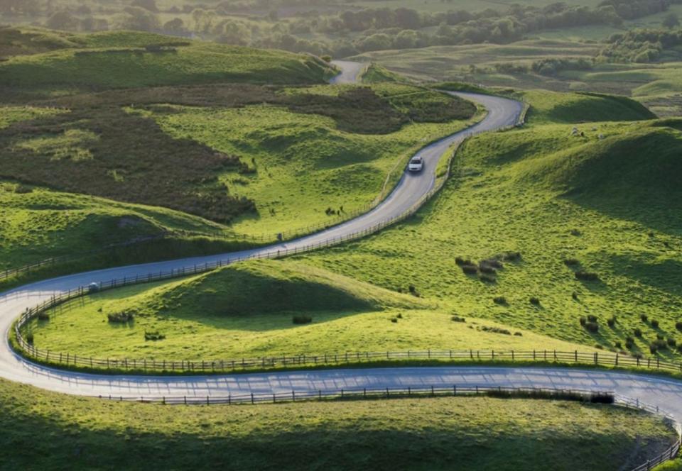 Car on road through green hills landscape