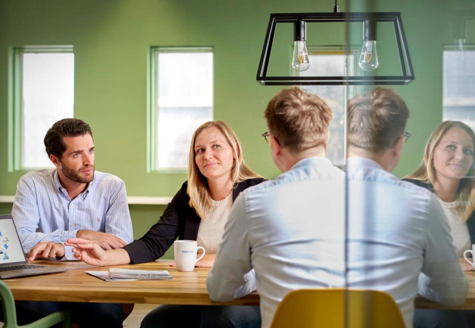 two men and a woman sitting at a meeting table